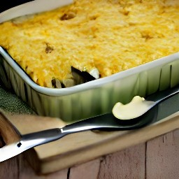 a casserole dish with summer squash and shredded cheddar cheese on top.