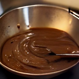a bowl full of batter containing brown sugar, granulated sugar, vanilla extract, cocoa powder, and vegetable oil.