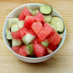 a bowl of watermelon cubes, cucumber slices, and chopped jalapeno peppers mixed with red wine vinegar and salt.