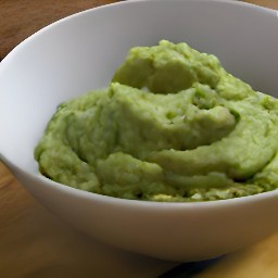the avocado halves are mashed into a bowl with a fork.