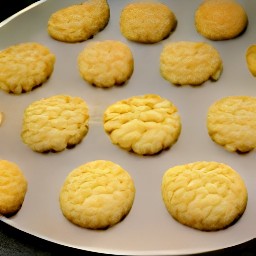 the baking sheet contains orange cream cheese cookies that are ready to be served.