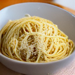 a bowl of spaghetti with dressing and parmesan cheese mixed together.