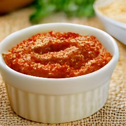 a bowl of pesto with grated parmesan cheese and lemon zest.
