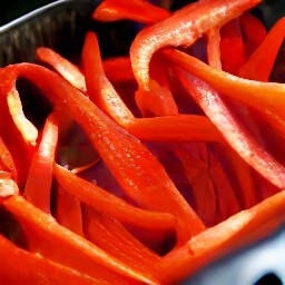 the red bell pepper strips are placed into a roasting tin.