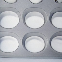 muffin cups are placed into a muffin tin.