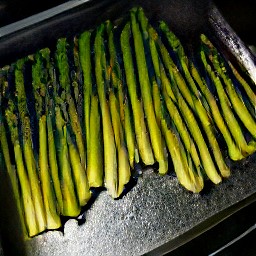 the asparagus is put on a baking sheet and drizzled with the soy mixture. it is then mixed together to marinate the asparagus. the baking sheet is placed in the oven for 15 minutes. afterward, the
