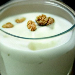 the yogurt mixture is in a glass. walnuts and honey are on the top.