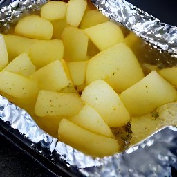 a tray of baked potatoes covered in rosemary and olive oil.