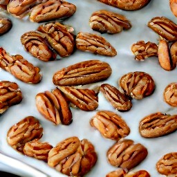 the pecans are coated and spread on a baking sheet lined with parchment paper.