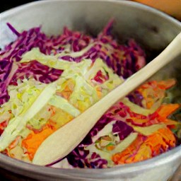 a salad made with grated cabbage, red cabbage, napa cabbage, scallions, red bell peppers and carrots.