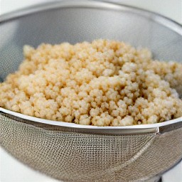 the cooked quinoa transferred to a sieve, and then rinsed with water.