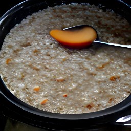 the peach mixture is in the crockpot. the crockpot is on low heat and the lid is off. the mixture has been stirred with a wooden spoon.