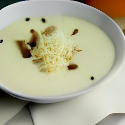bowls of cauliflower and chestnut soup with grated parmesan cheese, black pepper, and olive oil added to them.