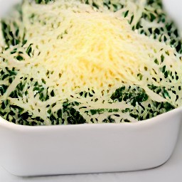 the grated gruyere cheese is scattered over the shallow ovenproof dish and the eggs are cracked on top.