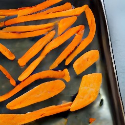 the sweet potato fries placed on a baking sheet, drizzled with olive oil, and then sprinkled with garlic salt, chilli powder, and cayenne pepper.