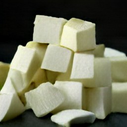 after trimming the zucchinis and dicing them, peel and chop an onion. then, cut tofu into cubes.