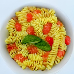 a bowl of pasta with diced plum tomatoes, minced garlic, chopped basil, and olive oil. the pasta is topped with grated parmesan cheese.