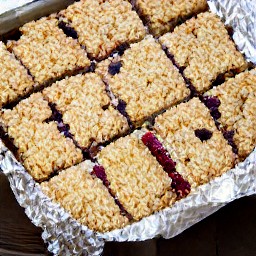 a baking dish full of peanut butter and granulated sugar mixture, with almond slices, grape-nuts cereals, rolled oats, and cranberries.