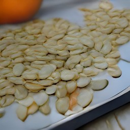 the pumpkin seeds are transferred to a baking sheet and olive oil is drizzled over them.