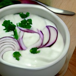 a bowl of yogurt mixture containing onions, celeriac, celery, lemon, parsley and oil.