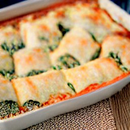 a baking dish with lasagna rolls covered in spaghetti sauce.