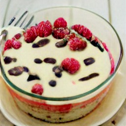 a bowl of batter containing crack eggs, granulated sugar, butter, vanilla extract, almond extract, melted chocolate, all-purpose flour mixture, chocolate chips and raspberries.