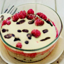 a bowl of batter containing crack eggs, granulated sugar, butter, vanilla extract, almond extract, melted chocolate, all-purpose flour mixture, chocolate chips and raspberries.