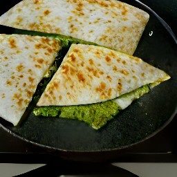 a flour tortilla with pesto, grated monterey jack cheese, crispy zucchini wedges and avocado slices.