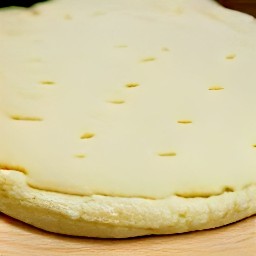 the pizza crust is in a baking sheet and the pizza topping mixture is spread on top.