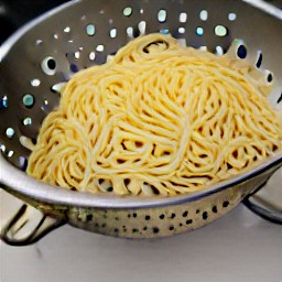 the cooked spaghetti is drained in a colander.
