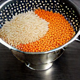 draining soaked lentils-rice in a colander.