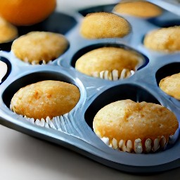 the muffin tin is taken out of the oven to get orange tea muffins.