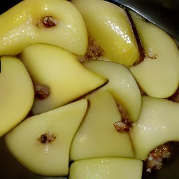 a dish containing cooked pears and walnuts in a sweet and sour sauce.