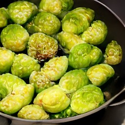 a dish of cooked brussels sprouts with sesame seeds.