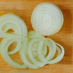 a peeled onion and garlic that are sliced.