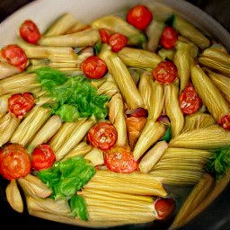 a pan of penne with cherry tomatoes, basil, garlic, and chili pepper flakes.