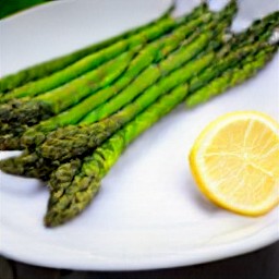 the roasted asparagus is transferred to a serving plate and garnished with lemon wedges.