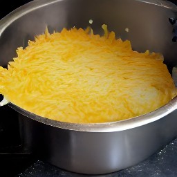 the casserole is removed from the oven, then the shredded cheddar is sprinkled on top and set aside for 2 minutes.