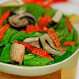 a salad with portabello mushrooms, veggies, bread cubes, and cheese.