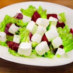 a salad with chopped lettuce, spinach, and beets. the salad is sprinkled with chopped walnuts and diced feta cheese. the salad is then drizzled with the vinaigrette.