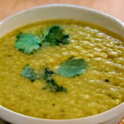 a serving bowl filled with dal and sprinkled with cilantro, which has been seasoned with salt.