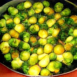 roasted brussels sprouts in a serving bowl with sauce on top.