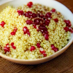 a platter with sugar and cinnamon sprinkled on it, garnished with candy-covered almonds and pomegranate seeds.