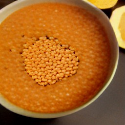 a bowl of spicy red lentils topped with lemon juice.