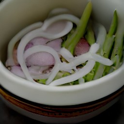 a bowl containing a mixture of shallot slices, asparagus, olive oil, black pepper, and half of the kosher salt.