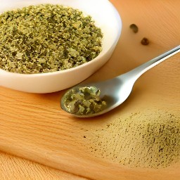 a bowl containing a mixture of olive oil, garlic, cider vinegar, mustard powder, capers, spearmint, basil and black pepper.