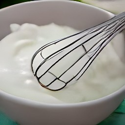 a bowl containing whisked eggs, plain yogurt, grated parmesan cheese, chopped basil, salt, and black pepper.