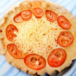the yogurt mixture is spread into the pie crust and the tomato slices are added. the rest of the grated parmesan cheese and chopped basil are scattered on top.