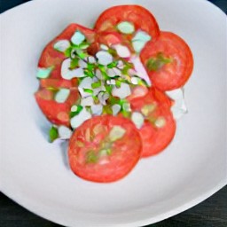 a platter with tomato slices and chopped onions, sprinkled with salt and scattered with chopped spearmint and chives on top.
