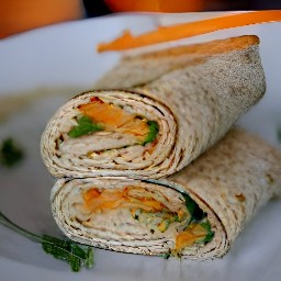 a whole wheat tortilla with hummus, carrots, arugula, and salt rolled up inside.